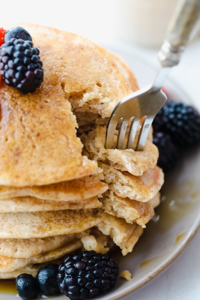 These tried and true Sourdough Pancakes are fluffy and delicious! They pair well with just about any toppings that you have on hand and they have just a touch of sweetness making adding maple syrup the final touch of heaven! Cutting a slice of sourdough pancakes with a fork.
