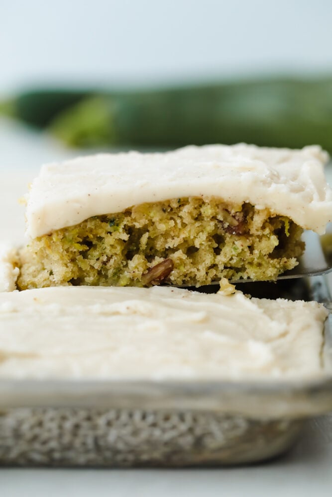 Zucchini Bars with Brown Butter Frosting is deliciously moist and absolutely heavenly. This is one of the best ways to use up those extra summer zucchini. Taking a slice out of zucchini bars.