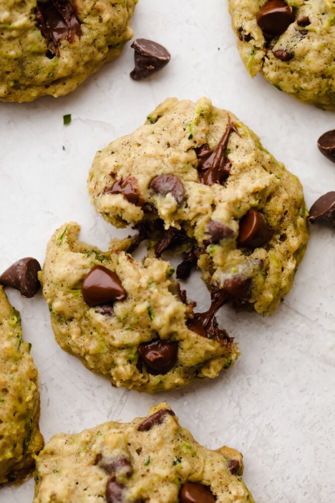 These zucchini oat chocolate chip cookies are a twist on the traditional cookie recipe and are absolutely delicious! Cookies are the ultimate comfort food that we all love and adore and after trying these, I bet you won't be able to just have one!! Cookie broken in half with melted chocolate chips.