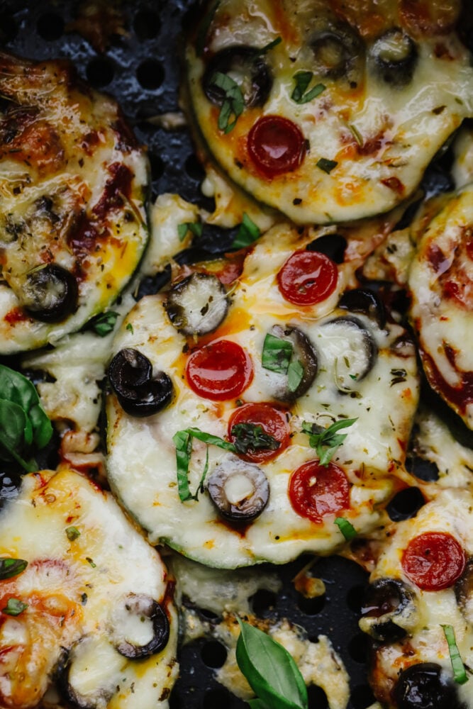 Air Fryer Zucchini Pizza Bites are the perfect low-carb way to eat your pizza and love it too! Quick and easy these make a perfect snack, appetizer, or light meal any time of the week! Savory zucchini bites garnished with fresh basil.
