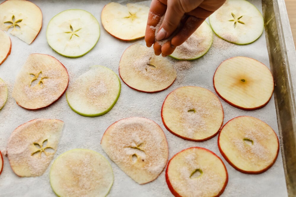 Baked Cinnamon Sugar Apple Chips is a healthy crunchy snack that is going to impress! Crunchy, crispy, sweet, and a bit spicy, these are going to change snack time Sprinkling apple slices with cinnamon and sugar.