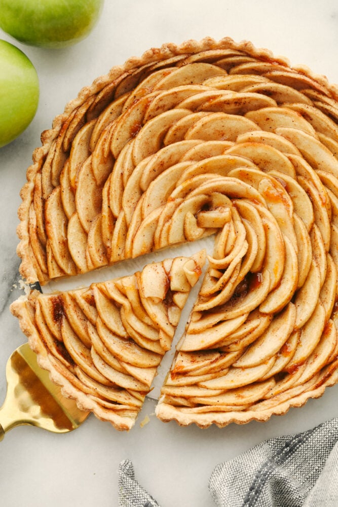 Loaded with fresh apples and baked to a perfect golden brown, this beautiful apple tart is the pastry of the summer! A combination of buttery, nutty, and tart, it tastes as good as it looks! Taking a slice of apple tart.