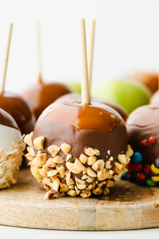 Celebrate fall by making these gourmet homemade caramel apples! They are the perfect blend of tart and sweet, topped with layers of indulgent caramel. Caramel apples topped with nuts and candies.