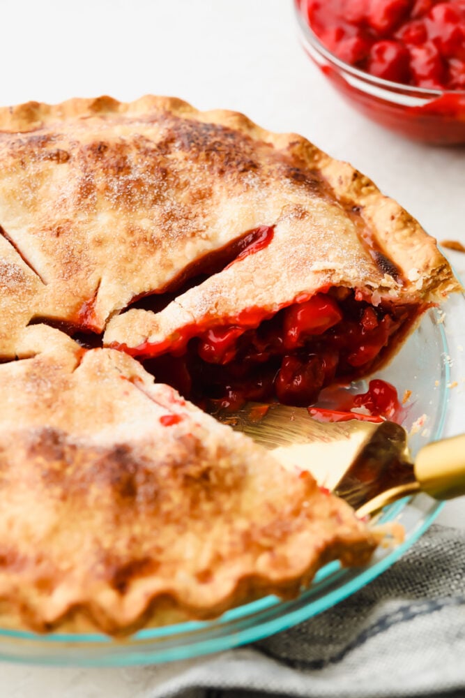 Homemade cherry pie is about as classic as they come and this recipe is no exception! Absolutely delicious, this mouthwatering pie has a tart filling and flaky crust that is so tasty that you won't be able to stop at just one slice! A cherry pie with a pie server.