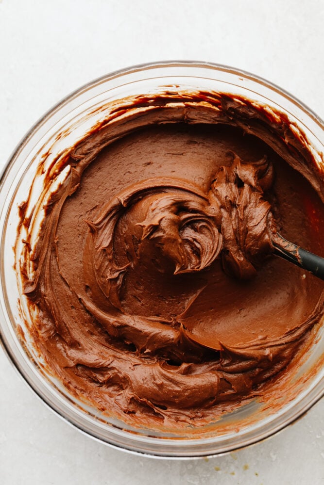 Chocolate buttercream frosting is creamy, smooth, rich, and mouthwatering! The chocolate flavor is absolutely incredible and you will want to add it to every single treat that you bake up this fall! Chocolate buttercream frosting in a bowl stirred together.