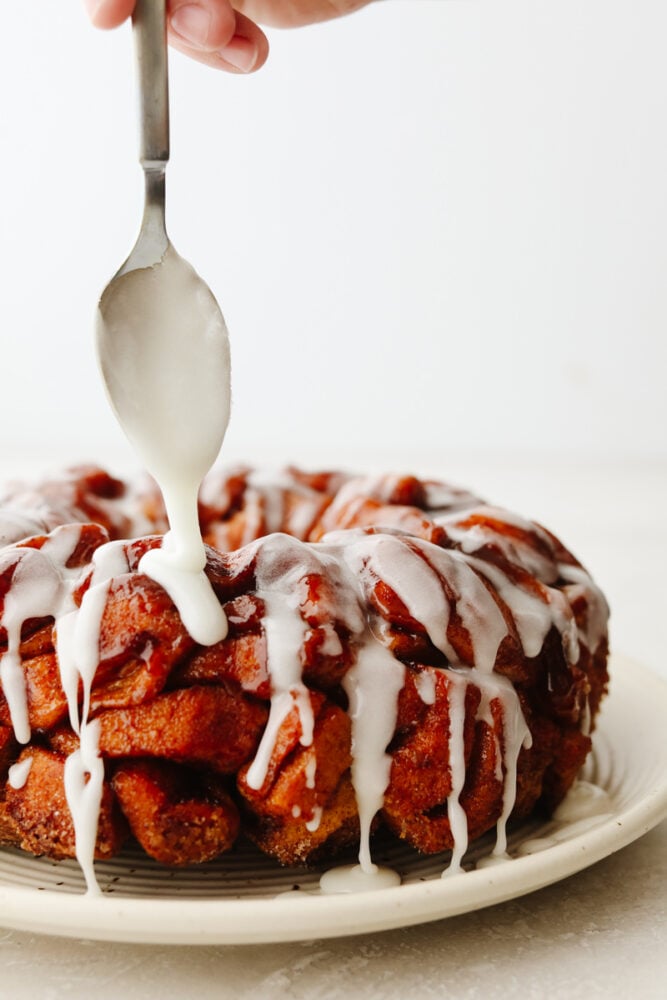 Cinnamon roll monkey bread is the easiest pull-apart dessert! It is amazingly soft, warm, and layered in decadent icing. Drizzling icing on cinnamon roll monkey bread.
