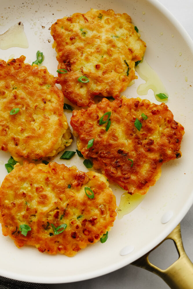 Corn Fritters are the best combination of savory tastes that are cooked to golden brown perfection! Crispy on the outside with a soft and tender inside, these are insanely delicious! Corn fritters on a plate garnished with green onions.