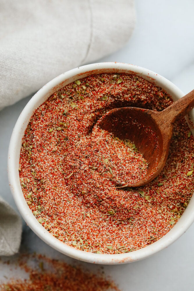 Cajun seasoning is the perfect blend of spices to add a little zest to your dish. Completely versatile and delicious, this homemade spice can be added to a wide variety of recipes giving them just the yummy kick you were looking for! Cajun seasoning with a spoon.
