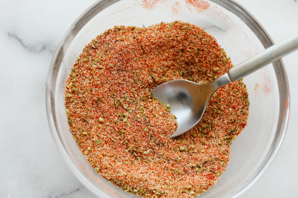 Cajun seasoning is the perfect blend of spices to add a little zest to your dish. Completely versatile and delicious, this homemade spice can be added to a wide variety of recipes giving them just the yummy kick you were looking for! Cajon seasoning mixed in a bowl with a spoon.