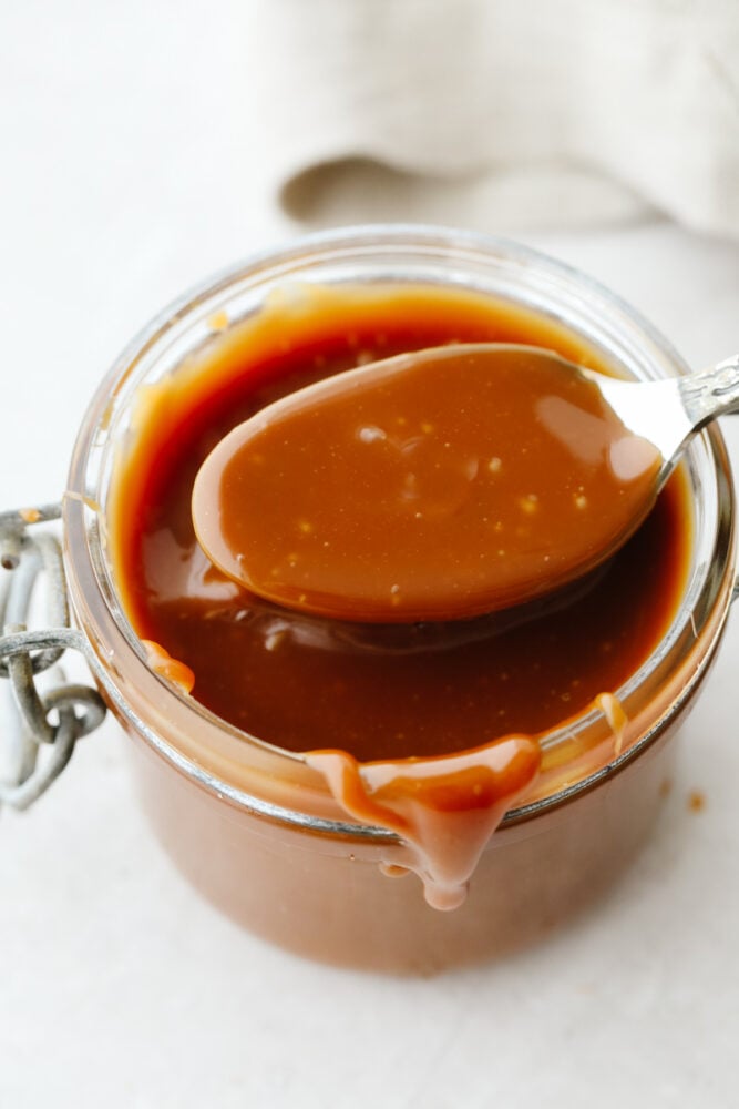 This homemade caramel sauce is straight from heaven! Its ooey-gooey, deliciously sweet flavor will have you over the moon excited, especially when you realize that you can add this to just about anything! Caramel on a spoon.