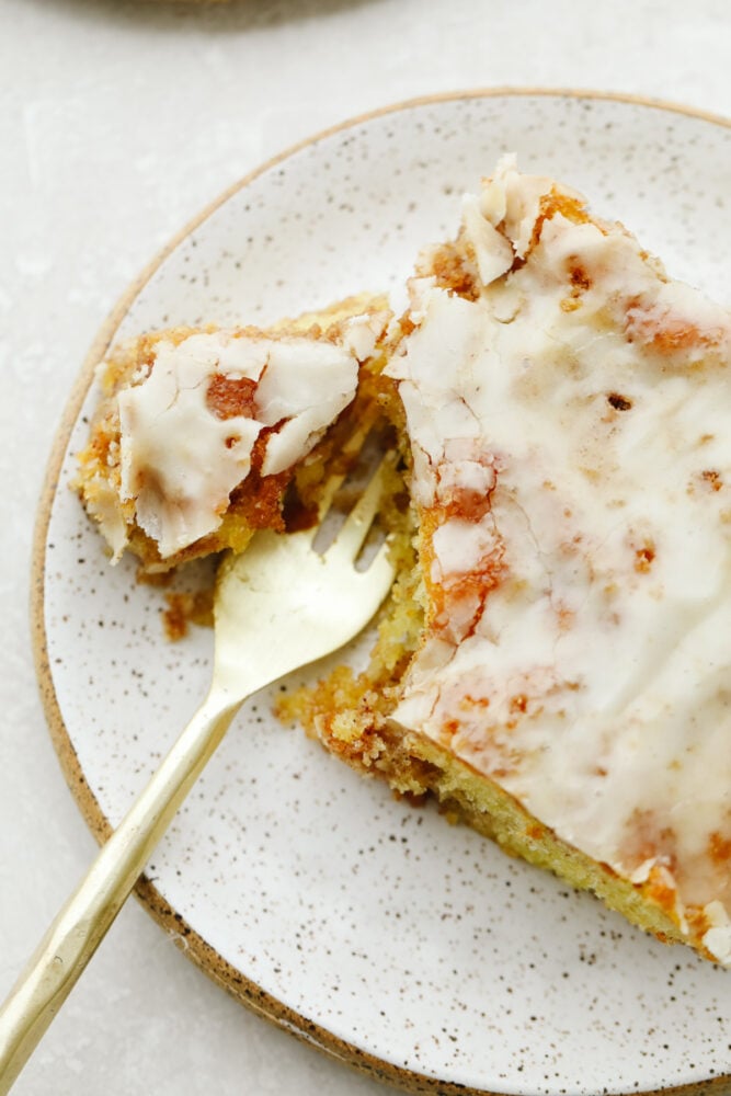 Honeybun cake is a super moist cake swirled with cinnamon and sugar and covered in a delicious vanilla glaze. Absolutely mouthwatering, this tried and true recipe tastes like a cinnamon roll but in cake form! Honeybun cake being cute with a fork.