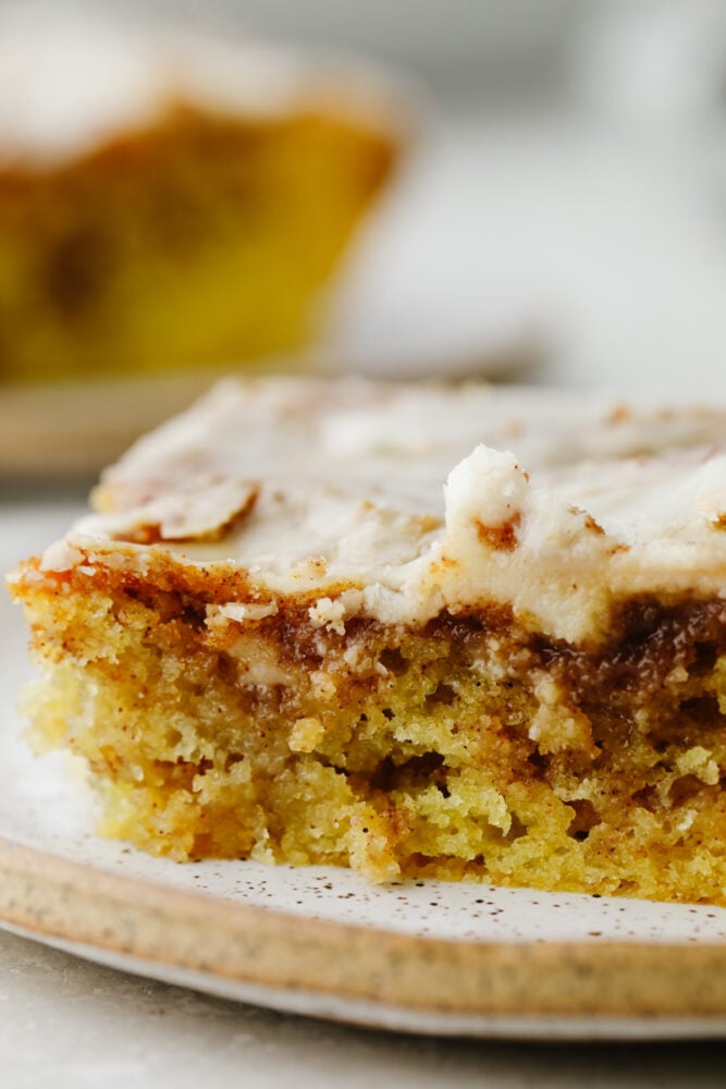Honeybun cake is a super moist cake swirled with cinnamon and sugar and covered in a delicious vanilla glaze. Absolutely mouthwatering, this tried and true recipe tastes like a cinnamon roll but in cake form! Honeybun cake on a plate.