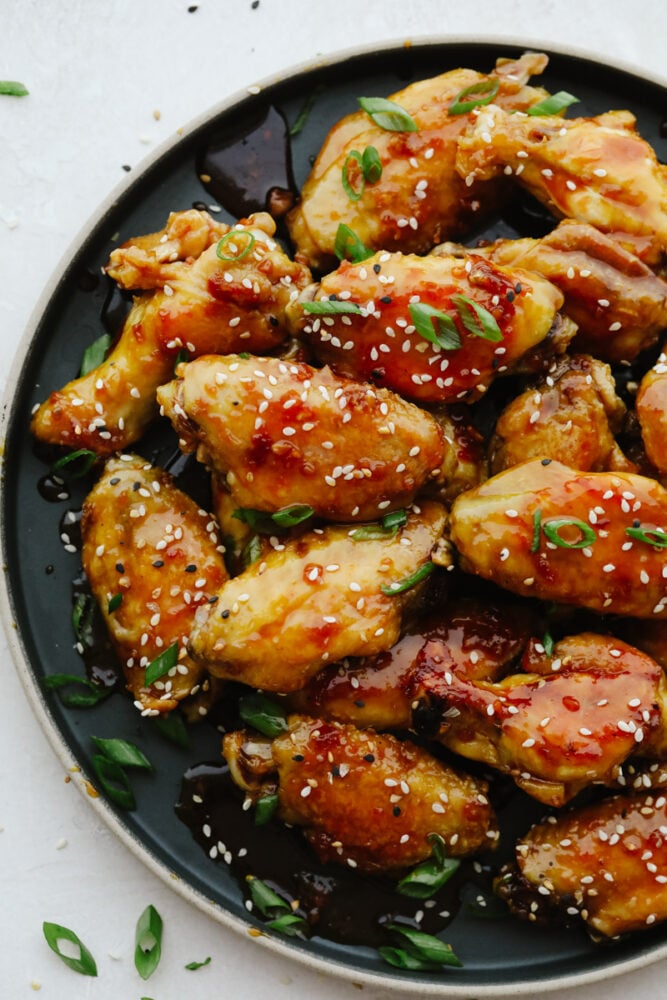 Sticky honey garlic wings are incredibly delicious and an excellent appetizer for absolutely any event or party! They have a mouthwatering, sweet taste that will keep you snacking all night long! Buffalo wings drizzled in sauce on a platter.