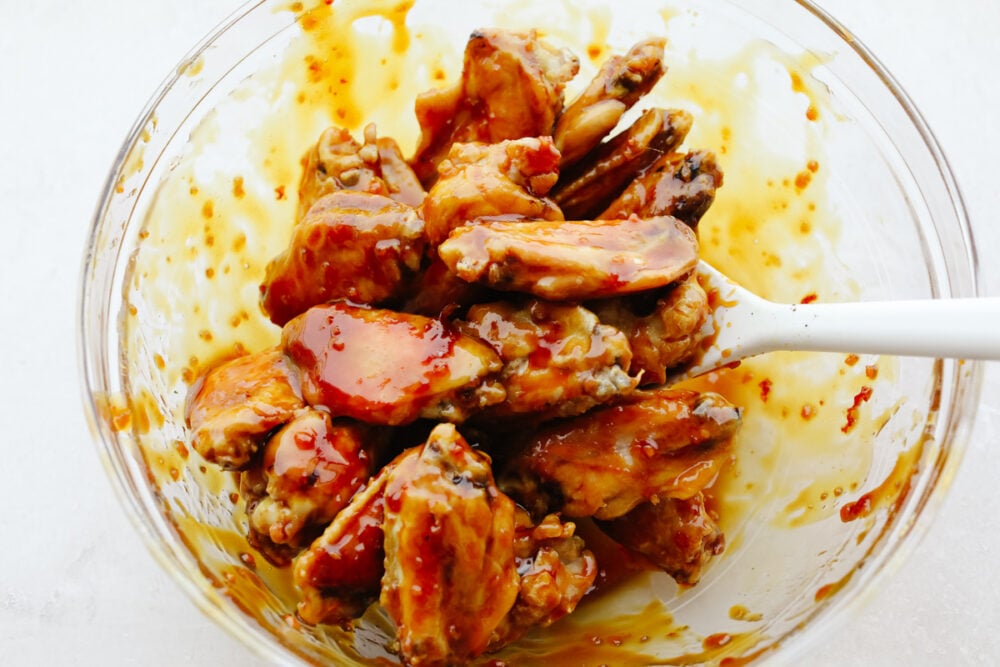 Sticky honey garlic wings are incredibly delicious and an excellent appetizer for absolutely any event or party! They have a mouthwatering, sweet taste that will keep you snacking all night long! Buffalo wings being mixed with sauce.