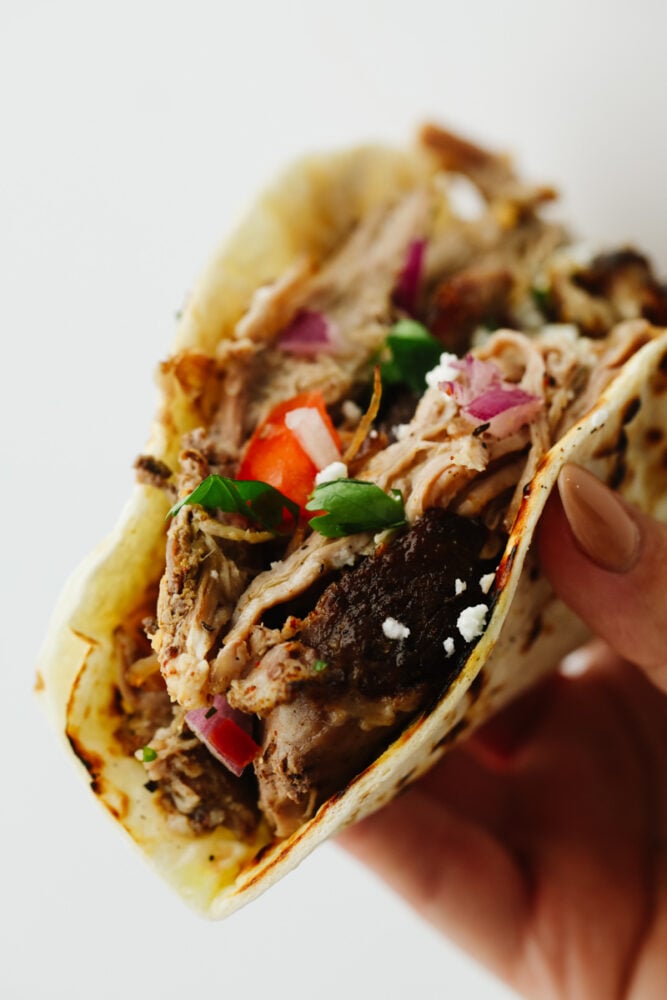Pork carnitas tacos are mouthwatering, juicy, and insanely delicious! They will satisfy even the pickiest of eaters and everyone will keep coming back for more! Zoomed in picture of a pork carnita taco.