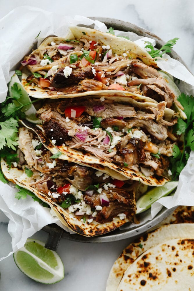 Pork carnitas tacos are mouthwatering, juicy, and insanely delicious! They will satisfy even the pickiest of eaters and everyone will keep coming back for more! Pork carnita tacos in a dish.