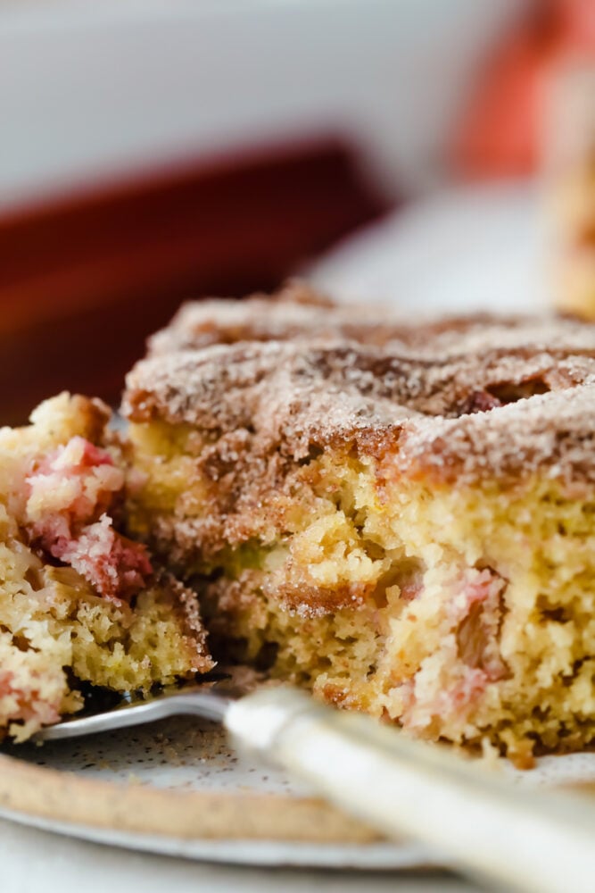 Cinnamon sugar rhubarb cake is a real crowd pleaser! The complementary ingredients of sweet and tart are incredible and are really going to knock your socks off! Cinnamon sugar rhubarb cake being served on a fork.