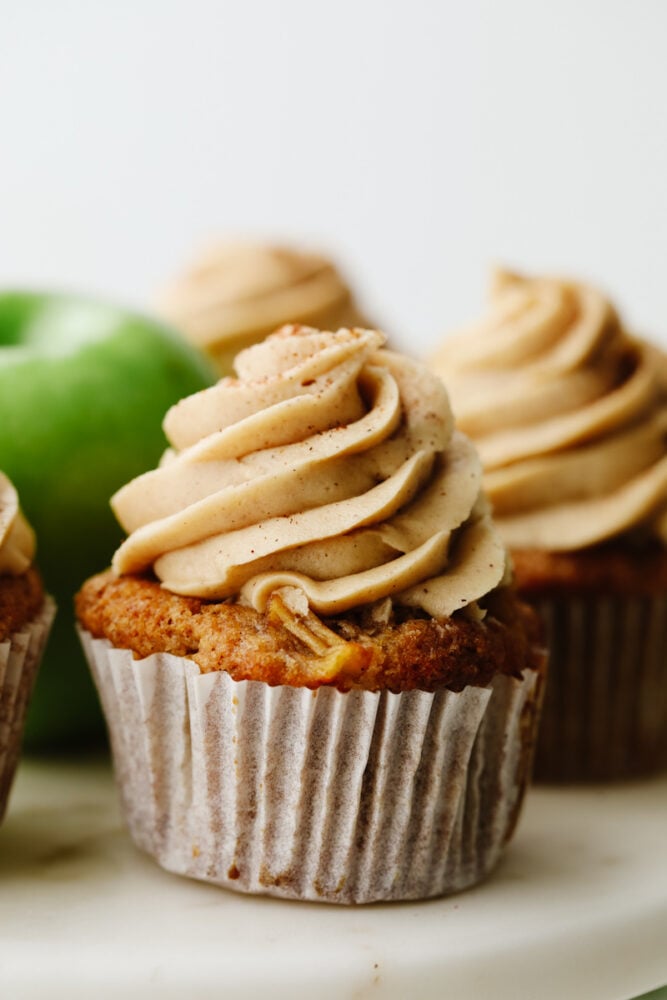 Apple pie cupcakes are a twist on a classic dessert. They are moist, delicious and with fresh apple pie filling in the middle, they give you JUST the right amount of texture! Close up of an apple pie cupcake.