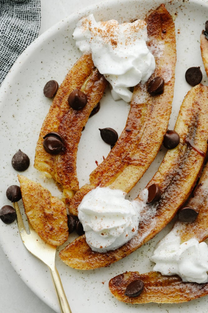Baked bananas are deliciously sweet with a touch of cinnamon and honey! They are baked to perfection and I love nothing more than a dessert that's easy AND made with fruit! Baked bananas topped with cinnamon and whipped cream.