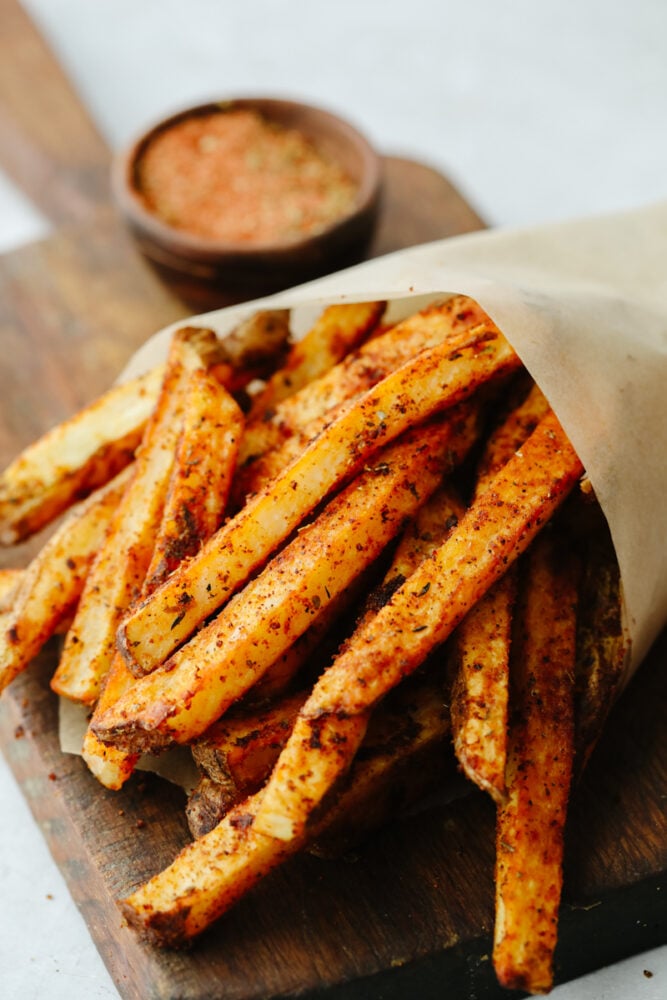 Cajun fries are baked to absolute perfection! With a delicious, spicy taste and crispy texture, I don't think that they get much better than this! Cajun fries wrapped up in parchment paper in a cone.
