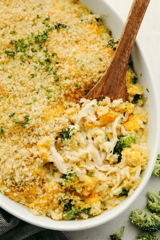 Broccoli and rice chicken casserole is a delicious, easy, family-friendly dish! It is creamy and filled with flavors that perfectly complement each other! You will love it! Broccoli, chicken and rice casserole with a wooden serving spoon in it.