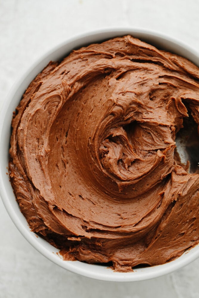 This chocolate cream cheese frosting is rich, smooth, and ready to enhance all of your desserts! It only takes 15 minutes of prep and a few super simple ingredients to create chocolatey perfection. A white bowl filled with chocolate cream cheese frosting.