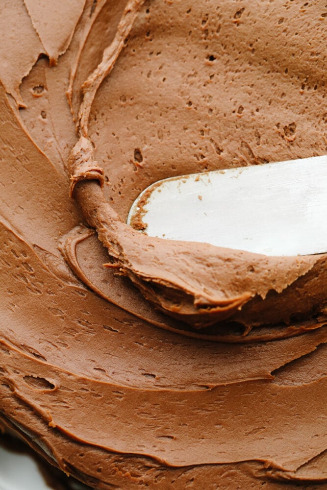 This chocolate cream cheese frosting is rich, smooth, and ready to enhance all of your desserts! It only takes 15 minutes of prep and a few super simple ingredients to create chocolatey perfection. Mixing frosting with an icing spatula.