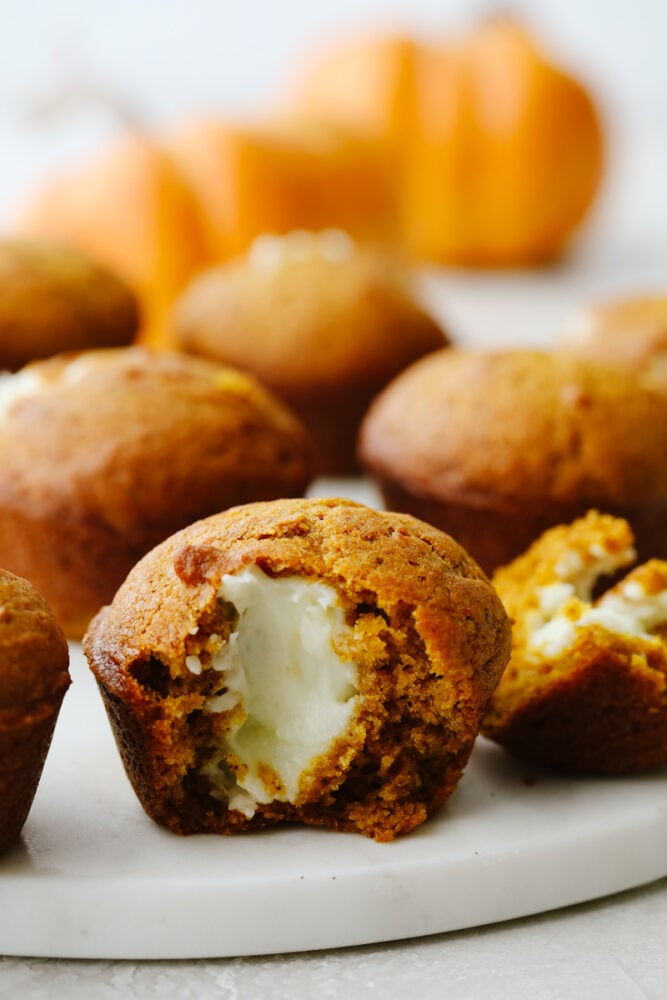 These pumpkin cream cheese muffins are the perfect combination of moist and savory on the outside and sweet and tangy on the inside! Pumpkin season is officially underway and these muffins are here for it! Pumpkin muffin cut in half showing cream cheese in the middle.
