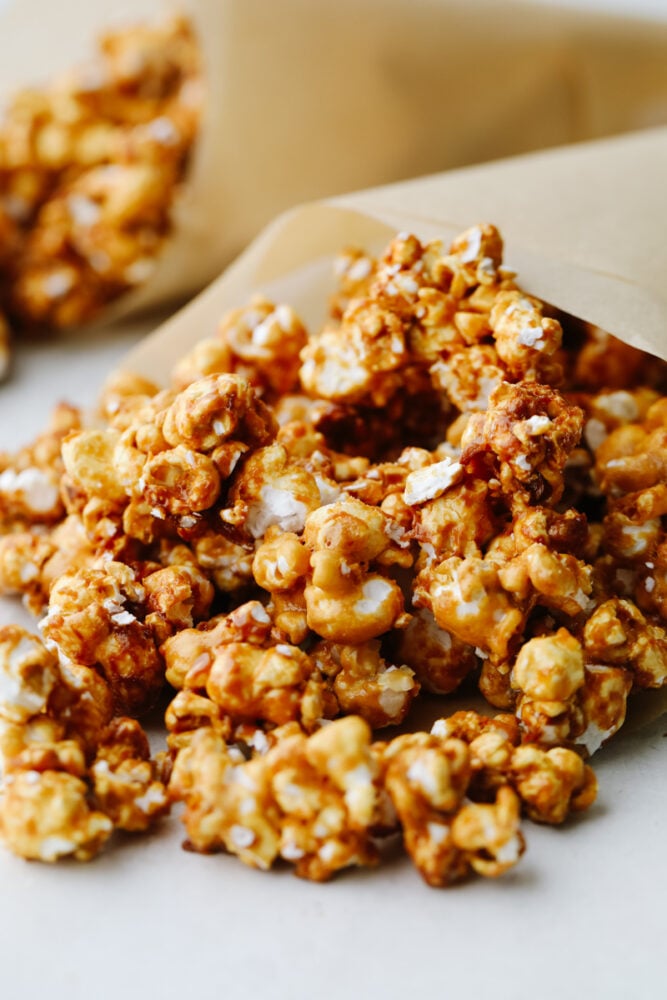 Crunchy caramel corn is absolutely divine! This classic crunchy snack delivers on that deep, rich caramel flavor that we all know and love! Eat it at home or on the go...Either way, you're going to be hooked! Crunchy caramel corn on some parchment paper.