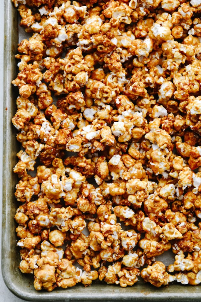 Crunchy caramel corn is absolutely divine! This classic crunchy snack delivers on that deep, rich caramel flavor that we all know and love! Eat it at home or on the go...Either way, you're going to be hooked! Caramel corn on a baking sheet that is cooked and crunchy.