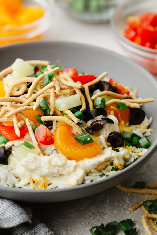 Hawaiian haystacks are the ultimate layered comfort food! Rice, shredded chicken, and hearty gravy combine with your favorite toppings in this easy dinner. A Hawaiian haystack topped with various toppings in a gray bowl.