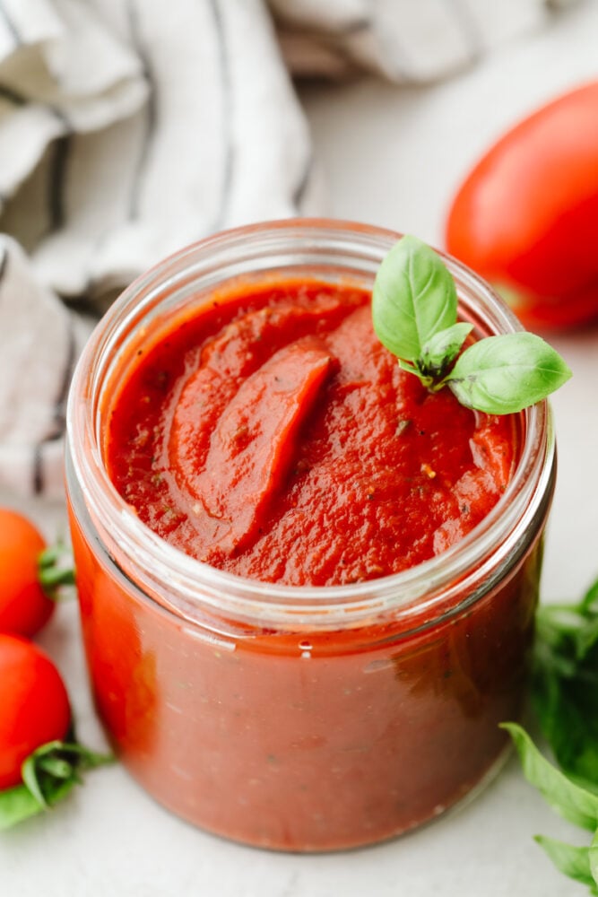 Using homemade pizza sauce is the perfect way to level up your pizzas! It's loaded with sautรฉed garlic, fresh herbs, and only takes 5 minutes to make! A jar of homemade pizza sauce with