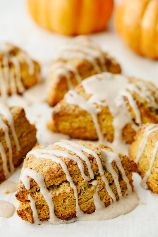 Pumpkin scones are absolutely mouthwatering and delicious! Filled with pumpkin flavor and drizzled with cinnamon icing, this is a breakfast option that you won't be able to pass up! A close up of a pumpkin scone.