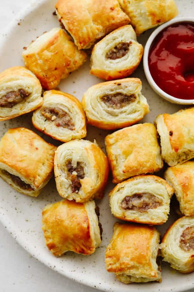 Sausage rolls are perfectly flaky, savory, and absolutely delicious! The best appetizer or snack, these sausage rolls will for sure be a hit among your party guests! Sausage rolls on a platter with ketchup.