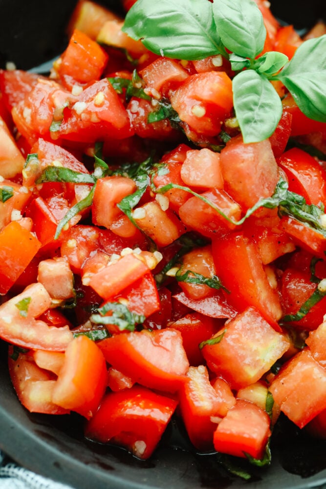 Showcase fresh tomatoes with this light and refreshing tomato basil salad! It's tossed with aromatic herbs, olive oil, and vinegar for fresh, bright flavor that is hard to resist! Closeup of tomato basil salad.