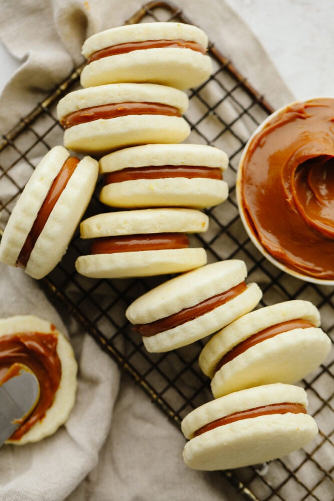 These alfajores cookies are simply divine! Their texture is perfectly soft and once you add in that creamy dulce de leche filling, well... Let's just say these cookies aren't going to last long! Finished alfajores cookies on a cooling rack.