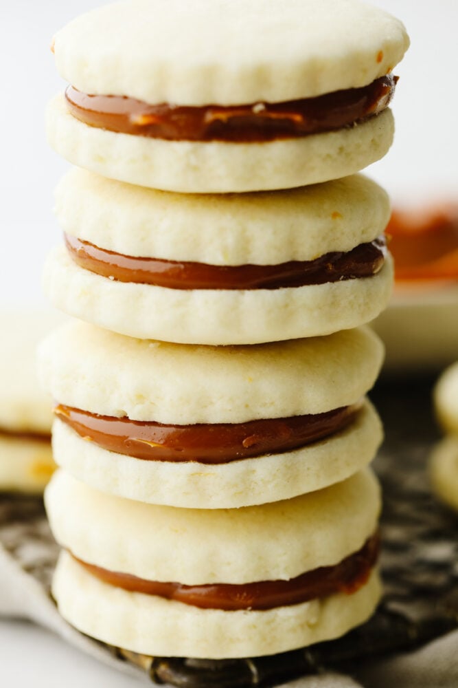 These alfajores cookies are simply divine! Their texture is perfectly soft and once you add in that creamy dulce de leche filling, well... Let's just say these cookies aren't going to last long! A close up picture of a stack of alfajores cookies.