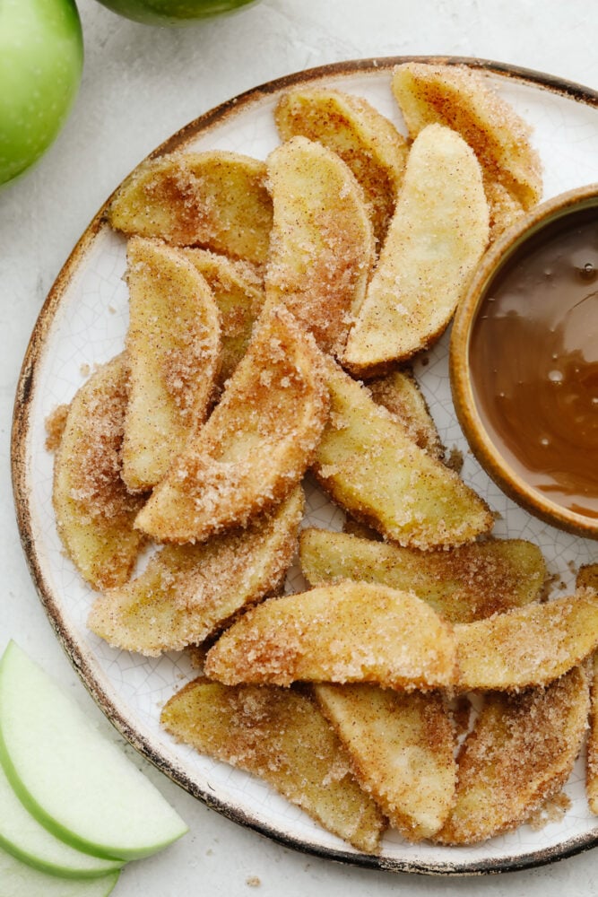 Lightly battered and tender, apple fries are going to become your new favorite treat! A generous coating of cinnamon sugar and homemade caramel dip make them even more irresistible! A plate of apple fries with caramel dip.