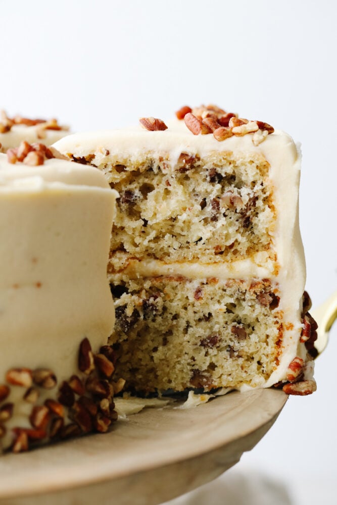 Soft, tender, and filled with nutty goodness, this butter pecan cake is perfect for fall! Browned butter cream cheese frosting and fresh chopped pecans make each bite a dream. Taking a slice of butter pecan cake.