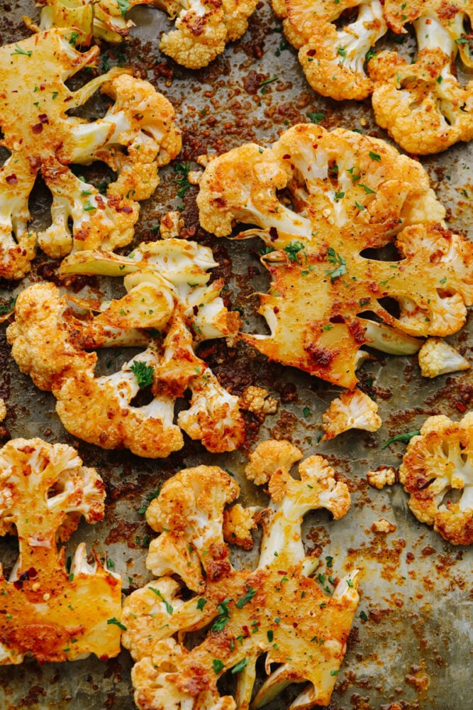 Making roasted cauliflower steaks is the best way to show all this veggie has to offer! They're amazingly tender and tossed in a mouthwatering blend of garlic, paprika, and parmesan. Roasted cauliflower on a baking sheet.