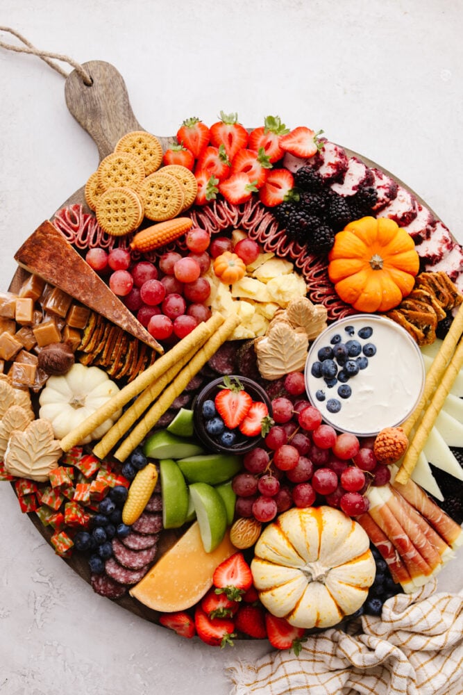 This fall charcuterie board is easy to make and is perfect for all of the parties this season! Packed with colorful and delicious food it is sure to be a hit with all of your guests! A fall charcuterie board filled with fruits, cheese, meat and crackers.