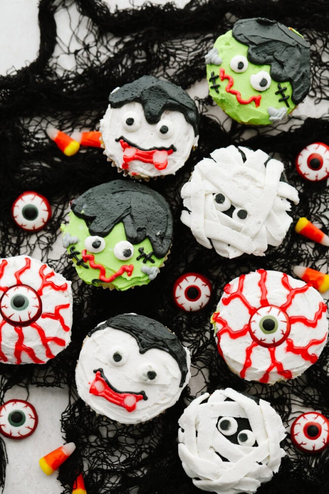 Halloween cupcakes are as tasty as they are cute! Moist vanilla cupcakes are frosted with timeless Halloween characters for an unforgettable treat! Various Halloween cupcakes served on black netting.