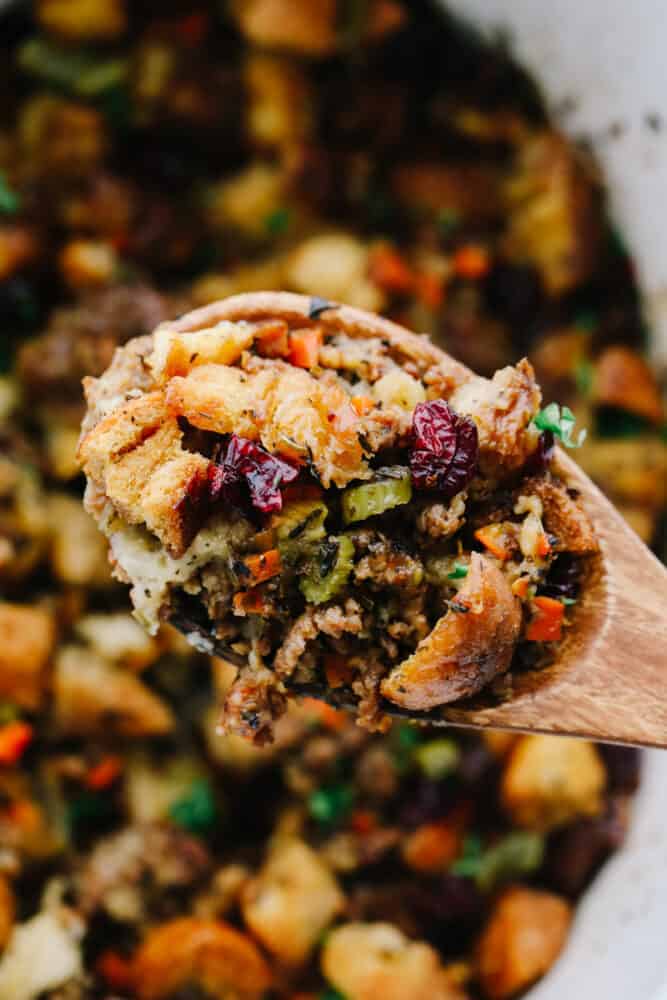 This classic sausage herb stuffing is full of an amazing mixture of flavors! The spices used in this are the star of the show and it will be a side dish that everyone goes crazy over! Sausage herb stuffing being served with a wooden spoon.