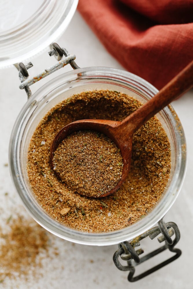 Jerk seasoning is the most deliciously sweet and savory blend of spices! It's simple to use and even more easy to make! You will have yourself a custom homemade seasoning in less than 5 minutes! Jerk seasoning in a jar with wooden spoon.