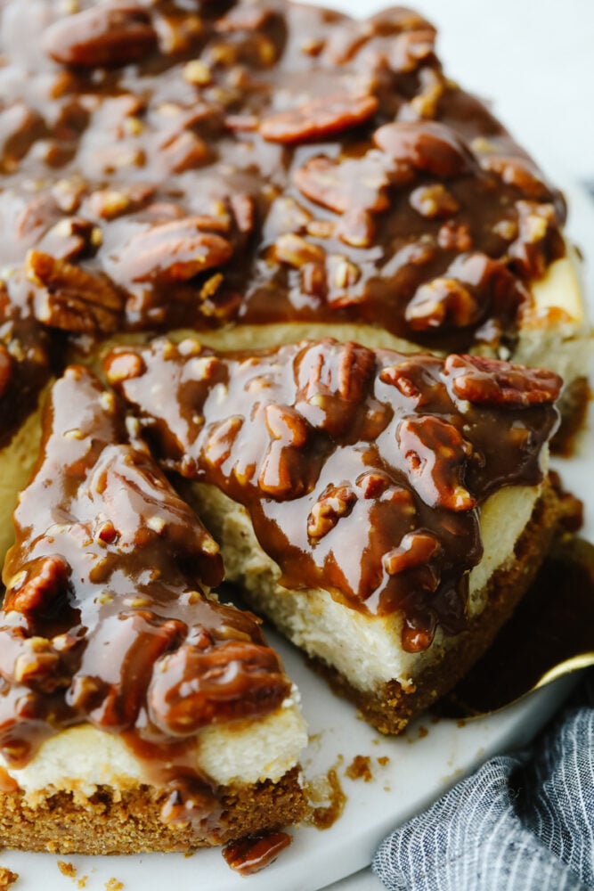 This dessert is everything you love about pecan pie, drizzled on the most decadent, creamy cheesecake! Each bite of pumpkin pie cheesecake will wow you! A pecan pie cheesecake cut into pieces.