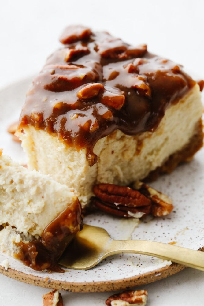 This dessert is everything you love about pecan pie, drizzled on the most decadent, creamy cheesecake! Each bite of pumpkin pie cheesecake will wow you! Taking a bite of cheesecake.