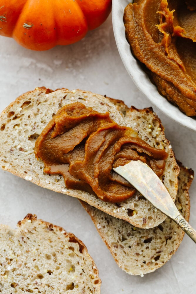 Pumpkin butter is thick, creamy, and delicious! It's super sweet with the perfect amount of pumpkin flavoring and can be put on basically anything! It's so delicious, your family will go crazy over it! Pumpkin butter being spread on toast with a butter knife.
