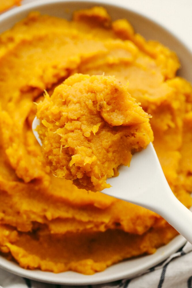 Pumpkin puree that is homemade cannot be beat! With its fresh taste and amazing texture, once you have tried this you will never go back! It is perfect for all of your fall recipes! A close up of pumpkin puree on a spoon.