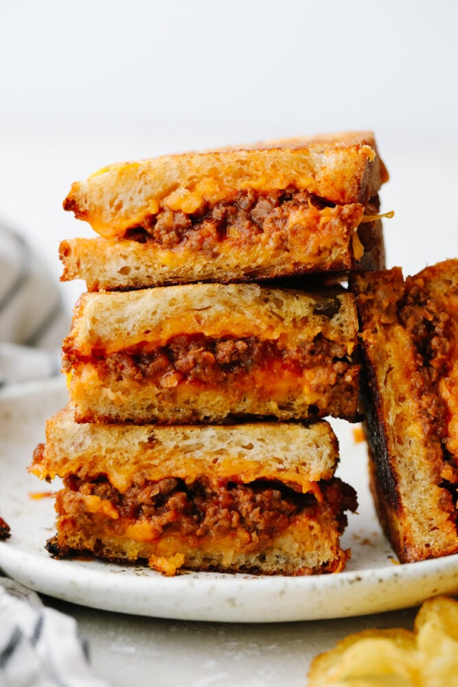 If you think a sloppy Joe grilled cheese sounds good, then just wait until you taste it! Tender, juicy and filled with flavor inside cheesy, crisped bread.. Well, it doesn't get much better than that! A sliced sloppy joe grilled cheese on a plate.