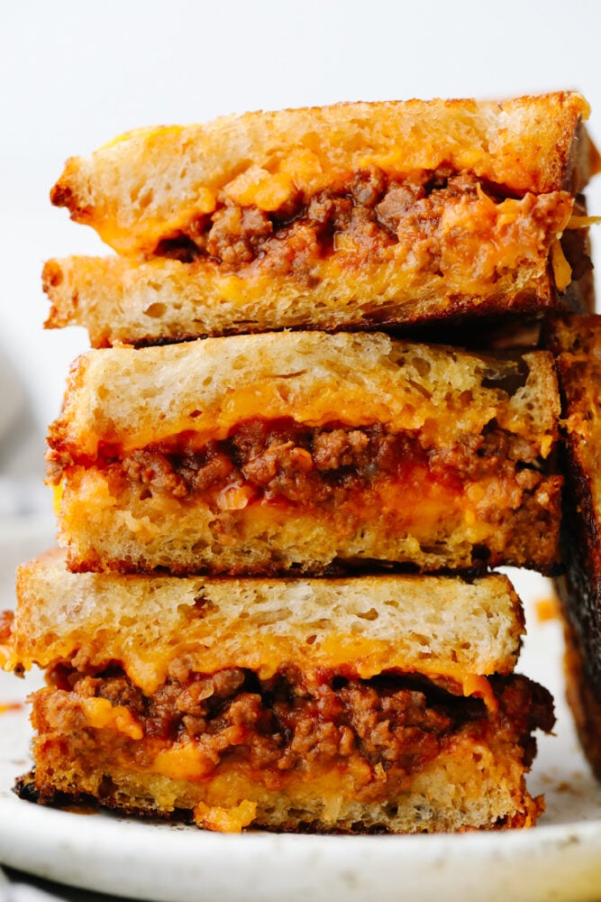 If you think a sloppy Joe grilled cheese sounds good, then just wait until you taste it! Tender, juicy and filled with flavor inside cheesy, crisped bread.. Well, it doesn't get much better than that! A stack of sliced sloppy joe grilled cheese sandwiches.